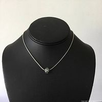 Front view of sterling silver necklace with single turquoise bead on black display.