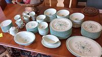 Full set of Noritake Paradise pattern china items arranged on table showing plates, bowls, cups, and serving pieces.