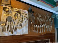 Wooden table with grouped flatware: knives on right, forks and spoons on left