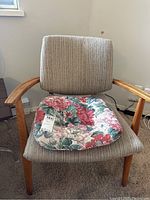 Front view of the wooden chair with striped fabric upholstery and floral seat cushion.