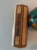 Close-up photo of the hexagonal Hawaii wind chime showing the wooden frame, woven panels, and vertical "HAWAII" inlay letters.
