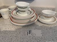Photo showing stacked dinner plates, sandwich plates, tea cups with saucers and additional cups.