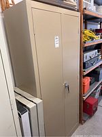 Closed beige metal cabinet with two doors and internal shelving.