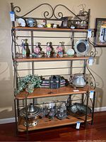 Front view of four-tier display shelf with metal frame and wood shelves with decorative scroll metalwork. Various decorative items on shelves not included.