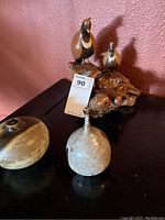 Front angled view of the driftwood carving with two birds and two pottery pieces placed on a dark surface.