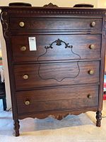 Front view showing five drawers, ornate carvings and brass hardware