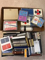 Photo of various playing card decks and two China card holders inside a box