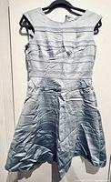 Full view of the Calvin Klein women's sky blue sleeveless dress with pleated details, hung on a black hanger, showing wrinkles in the fabric.