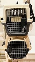 Two hard shell cat carriers stacked, medium and large sizes, showing front metal doors and plastic bodies