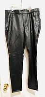 Full front view of black faux leather leggings on hanger showing slim fit and slight creasing in fabric.