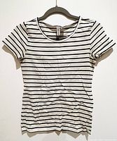 Photo of the full t-shirt hanging on a hanger showing the front of the black and white striped fitted t-shirt.