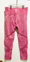 Full front view of pink leggings size L hung on hanger, featuring textured patterns and skull and crossbones logo on waistband.