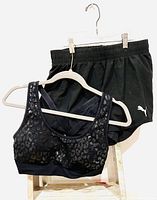 Photo of black Puma gym outfit with shorts and sports bra on hangers