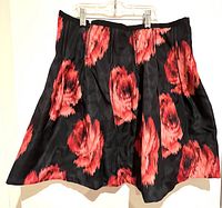 Full view of The Gap skirt with black base and large red/pink floral pattern, hanging from clips