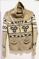 Front view of beige and black knit wool sweater with bee pattern, front zipper, shawl collar, and pockets