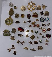 Top-down view of collection of varied antique and vintage pins laid out on white background showing many designs and styles.