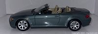 Side profile of the diecast BMW convertible toy car showing the metallic dark green paint and tan interior seats
