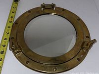 Top view of round brass mirror with measuring tape showing approx. 10 inches diameter.