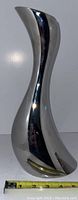Front view of curved hourglass Cobra vase, polished metal surface with measuring tape showing approx 11.5 inches tall.