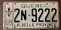 Front side of a 1969 Quebec license plate with embossed black letters on white background, including fleur-de-lis and La Belle Province designation.