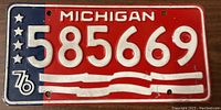 Front side photo showing red, white, and blue Michigan license plate with number 585669 and '76' logo.