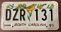Front of the South Carolina license plate with embossed alphanumeric DZR 131, yellow bird and flower graphics, and year 1991.