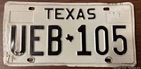 Front side of the Texas license plate UEB 105 showing embossed numbers and letters in black on a white background with some wear.