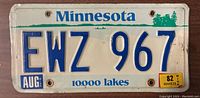 Front side of Minnesota license plate EWZ 967 showing text, numbers, stickers, and signs of wear.