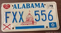 Front side of vintage Alabama license plate with embossed blue letters and 1979 stickers