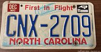 North Carolina license plate front showing embossed characters CNX-2709, 'First in Flight' and 'North Carolina' in red with state logo and 1991 registration stickers.