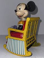 Side view of Minnie Mouse sitting in yellow rocking chair, showing tin litho detail and knitting piece