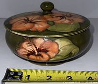 Side angle of the lidded bowl showing floral decoration and size approximately 4 inches in diameter.