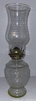 Full view of the vintage glass oil lantern showing diamond cut pattern glass font, metal burner, and glass chimney.