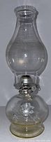 Front view of the vintage glass oil lantern showing clear chimney and etched floral design on globe base
