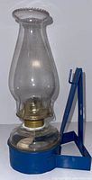 Front view of the vintage blue metal oil lantern with glass chimney and brass burner.
