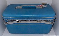 Blue Samsonite makeup luggage case closed, showing the shape, texture, and handle
