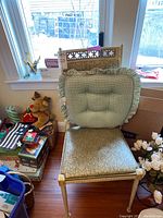 Front view of a dining chair showing vinyl seat, decorative wooden or metal backrest, with a green gingham cushion placed on seat.
