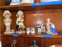 Shelf with two child Mann figurines, Noritake sugar dish with spoon, salt and pepper shakers, two deer figurines, and religious figurine.