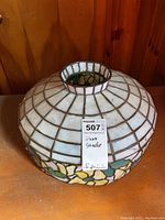 Top angled view of Tiffany style glass shade showing grid pattern with floral border and cracks.