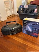 Magnavox boom box with carrying handle, cassette player, AM/FM radio, and ARTE LS-8248 lamp box on floor