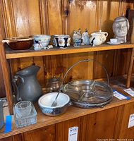 Shelf with pewter pitcher, ceramic bowls, metal carrier with glass snack server, assorted figurines, ceramic head sculpture