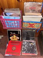 Two crates side by side on floor with loose LPs and four front-facing albums.
