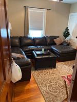 Full view of the black leather sectional sofa in the room showing layout and size