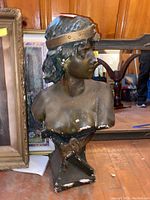 Front left angled view showing the bust's facial features, damaged edges, and textured hair with a headband.