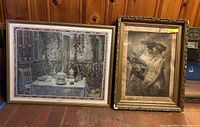 Two framed pictures side by side on wooden floor against wall, showing large color print of outdoor table on left and monochrome women print on right.