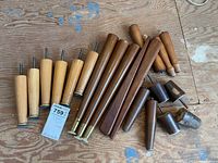Multiple mid-century modern wooden furniture legs, different sizes and finishes, laid out on wooden floor