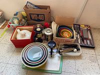 Overall view of various kitchenware items including nested Pyrex mixing bowls, coffee pots, cutters, utility tongs, and knives.