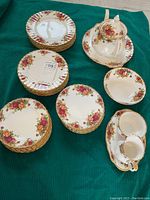 Overview of stacked plates, teapot, sugar bowl and creamer on green cloth