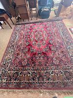 Full view of large vintage Eatonia rug partially rolled at one end showing floral pattern and fringed edges