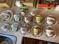 Photo of multiple floral pattern teacup and saucer sets laid out on a table showing six pairs